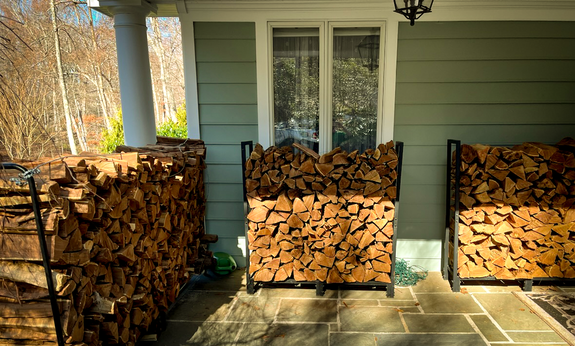 Stacks of kiln dried firewood on metal racks outside a house